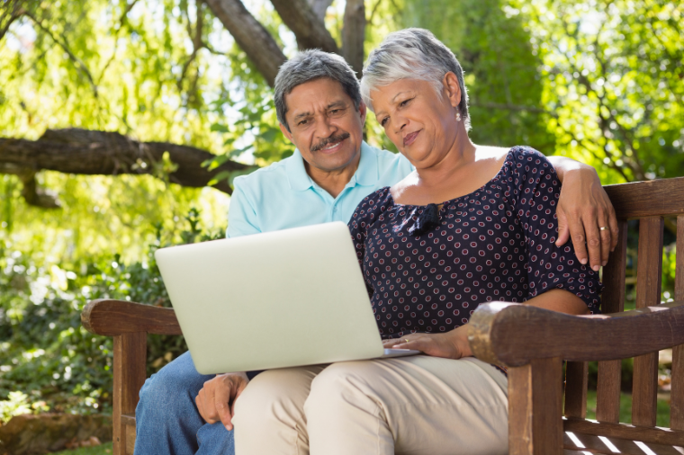 Latino couple middled aged looking at laptop